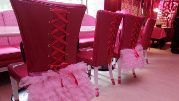 Dekorierte, pinkfarbene Stühle mit Rüschen und Schnürung in einem Restaurant.