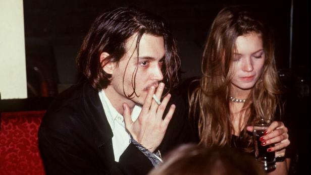 Johnny Depp raucht eine Zigarette, während Kate Moss ein Getränk hält.