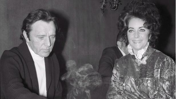 Ein Schwarzweißfoto von Elizabeth Taylor und Richard Burton, umgeben von Rauchschwaden.