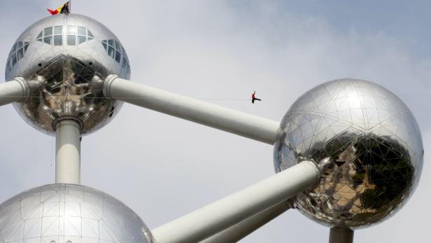 Ein Mann balanciert auf einem Seil zwischen den Kugeln des Atomiums in Brüssel.