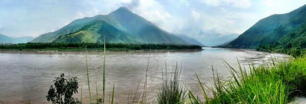 Eine weite Flusslandschaft mit Bergen im Hintergrund.