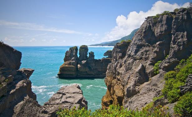 Die Pancake Rocks ragen an der Küste Neuseelands aus dem türkisfarbenen Meer.