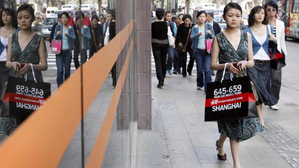Eine Frau mit einer H&M-Einkaufstasche in Shanghai geht die Straße entlang.