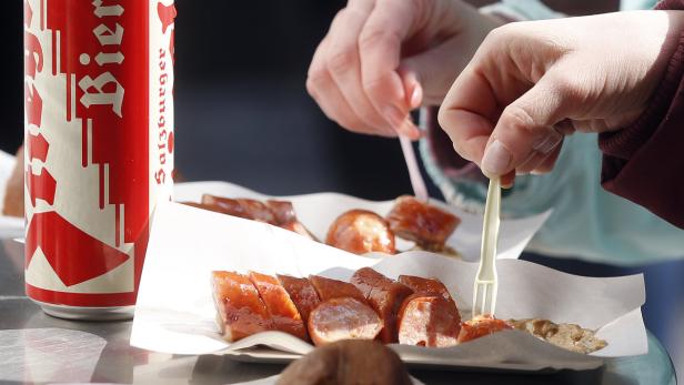 Eine Dose Salzburger Bier und eine Portion Bratwurst mit Senf werden gegessen.