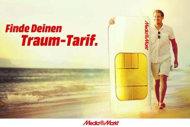 Ein Mann geht am Strand und hält eine übergroße SIM-Karte von Media Markt.