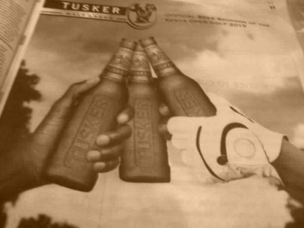 Drei Flaschen Tusker-Bier werden von einer Hand und einem Golfhandschuh gehalten.