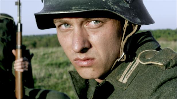 Ein Soldat mit Stahlhelm und Gewehr im Feld.