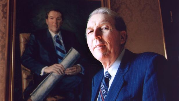 Ein Mann steht vor einem Porträt von sich selbst.