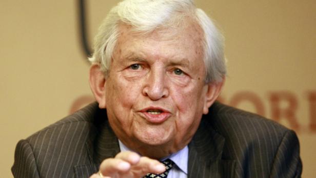 Nahaufnahme eines älteren Mannes in einem gestreiften Anzug, der gestikuliert.