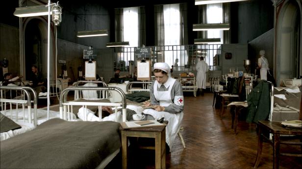 In einem Lazarett schreibt eine Krankenschwester des Deutschen Roten Kreuzes Notizen.