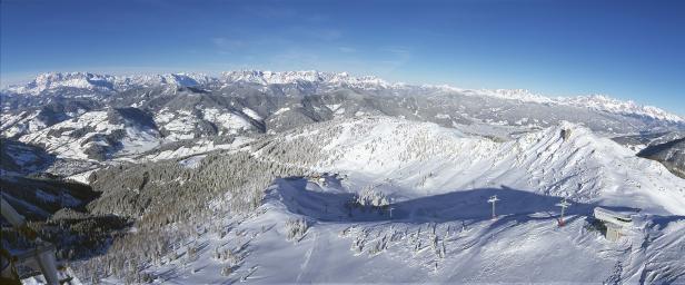 Panoramaaufnahme einer verschneiten Berglandschaft mit Skipisten und Liftanlagen.