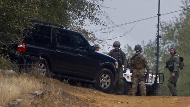 Eine Gruppe von Soldaten steht neben einem schwarzen Geländewagen und einem Militärfahrzeug.