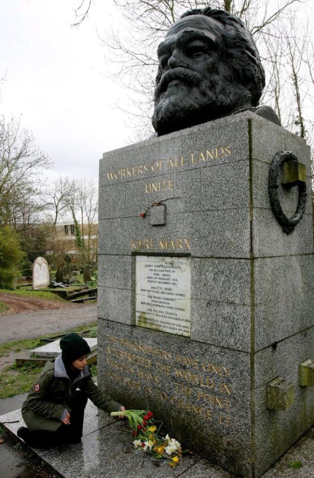 Eine Frau legt Blumen am Grabmal von Karl Marx auf dem Highgate Cemetery in London nieder.