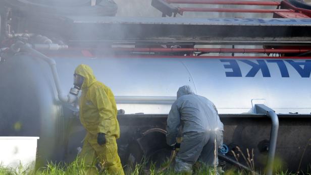 Zwei Personen in Schutzanzügen arbeiten an einem Tankwagen der Marke Talke.