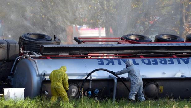 Zwei Personen in Schutzanzügen arbeiten an einem umgekippten Tanklastwagen der Firma Alfred Talke.
