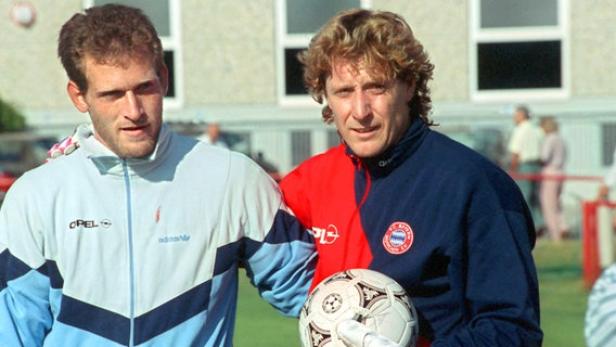 Zwei Fußballtrainer, vermutlich vom FC Bayern München, posieren mit einem Ball.