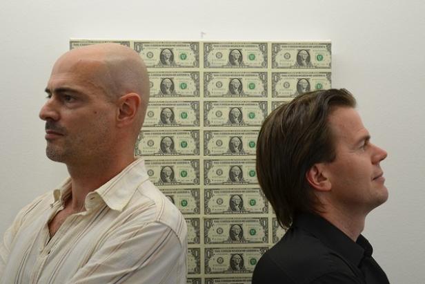 Zwei Männer stehen vor einem Kunstwerk, das aus US-Dollar-Scheinen besteht.
