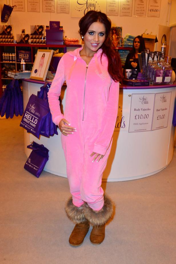 Eine Frau in einem rosa Overall und Stiefeln mit Fell steht an einem Stand von Amy Childs.