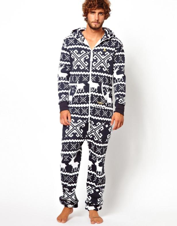 Ein Mann trägt einen marineblauen Onesie mit Weihnachtsmuster und Kapuze.