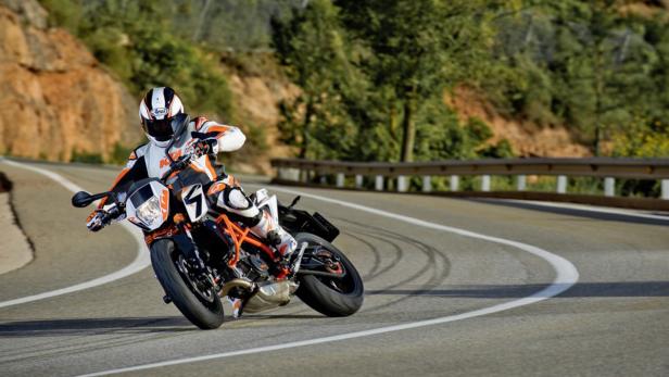 Ein Motorradfahrer fährt mit einer KTM auf einer kurvenreichen Straße.