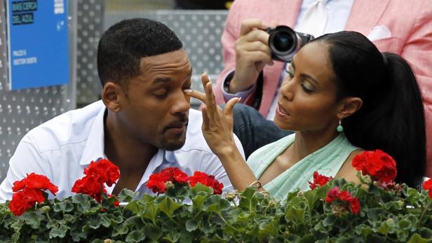 Jada Pinkett Smith spricht mit Will Smith, der sich das Auge reibt.