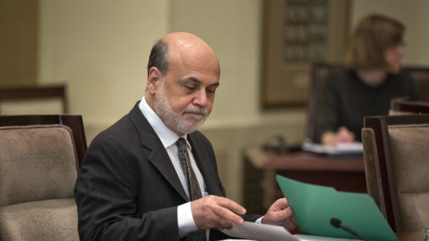 Ein Mann im Anzug sitzt an einem Tisch und liest Dokumente.