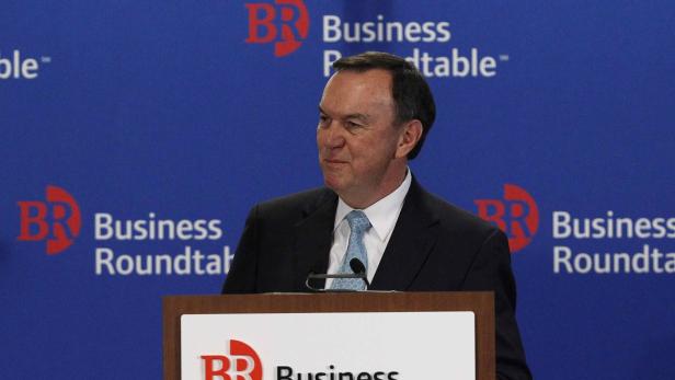 Ein Mann in Anzug steht vor einem Rednerpult mit dem Logo von Business Roundtable.