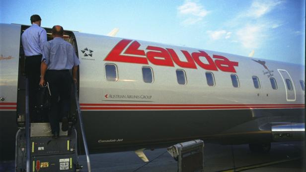 Zwei Männer steigen in ein Flugzeug der Lauda Air ein.
