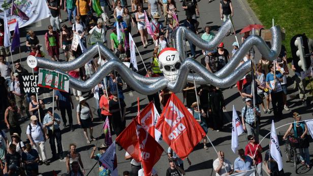 Eine Demonstration mit einer großen, silbernen Totenkopf-Figur und Protestschildern gegen TTIP und G7.