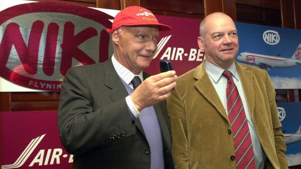 Niki Lauda mit einem Mobiltelefon vor Logos der Fluggesellschaft Niki.
