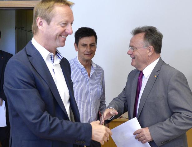 Drei Männer in Anzügen schütteln sich die Hände.