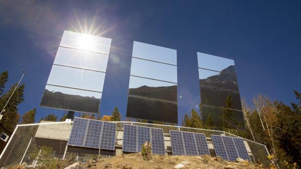 Spiegel reflektieren die Sonne und eine Berglandschaft auf einer Solaranlage.