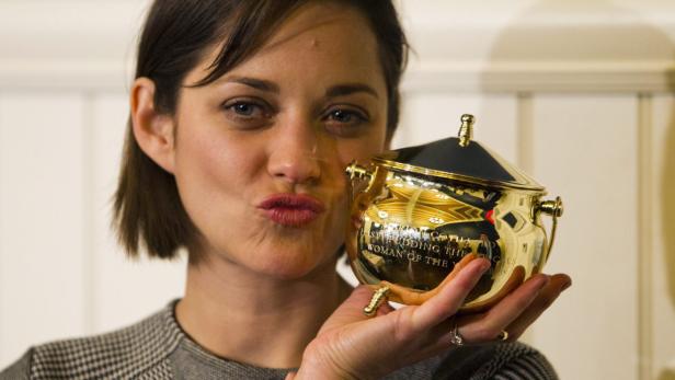Marion Cotillard hält eine goldene Trophäe in der Hand.