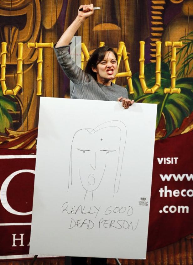 Eine Frau hält eine Zeichnung mit der Aufschrift „Really Good Dead Person“ hoch.