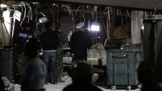 MEXICO PEMEX EXPLOSION Eine Gruppe von Personen steht vor einem zerstörten Gebäude.