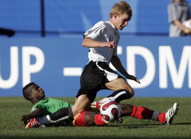 Zwei Fußballspieler kämpfen um den Ball auf dem Spielfeld.