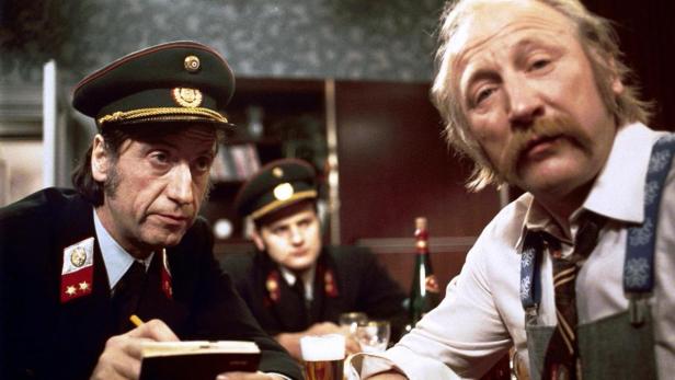 Zwei Polizisten und ein Zivilist sitzen an einem Tisch in einer Kneipe.