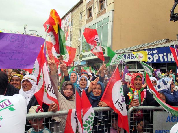 Eine Menschenmenge demonstriert mit HDP-Flaggen und kurdischen Farben in einer Stadt.