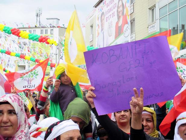 Eine Demonstration mit kurdischen Flaggen und einem Schild mit der Aufschrift „Kobani gegen Gezi“.