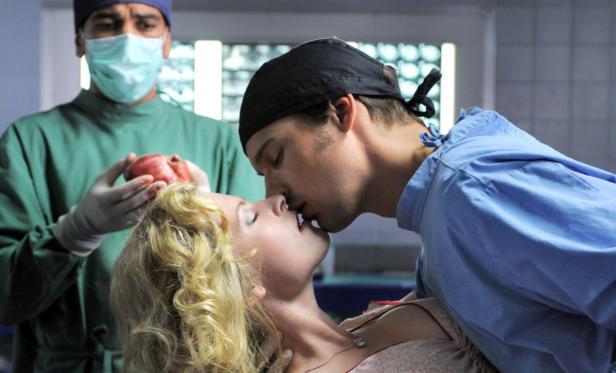 Ein Arzt küsst eine Patientin, während ein anderer Arzt ein Herz in den Händen hält.