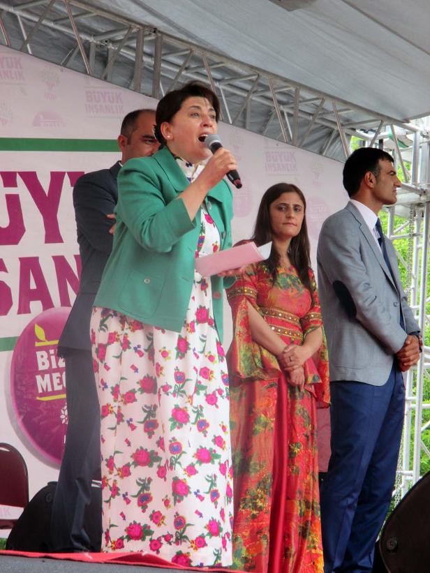 Eine Frau spricht auf einer Bühne mit Mikrofon zu einer Menschenmenge.