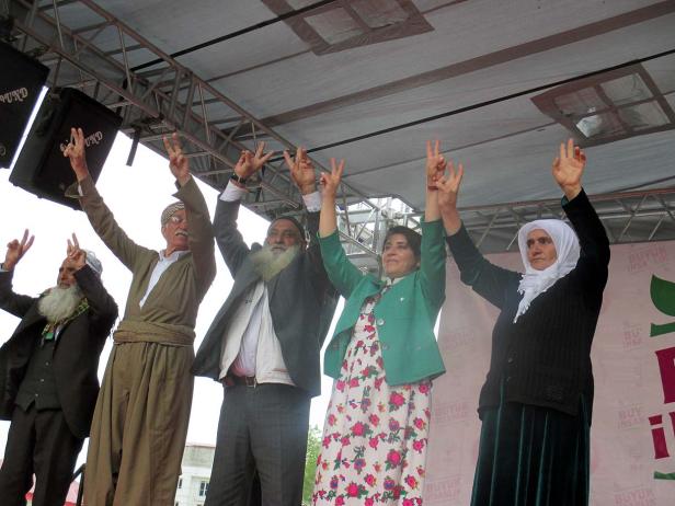 Eine Gruppe von Menschen auf einer Bühne zeigt das Victory-Zeichen.