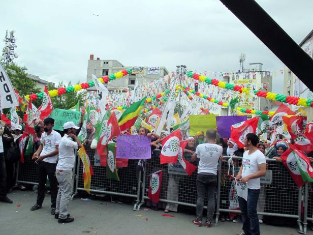 Eine Menschenmenge demonstriert mit HDP-Flaggen und Transparenten auf der Straße.