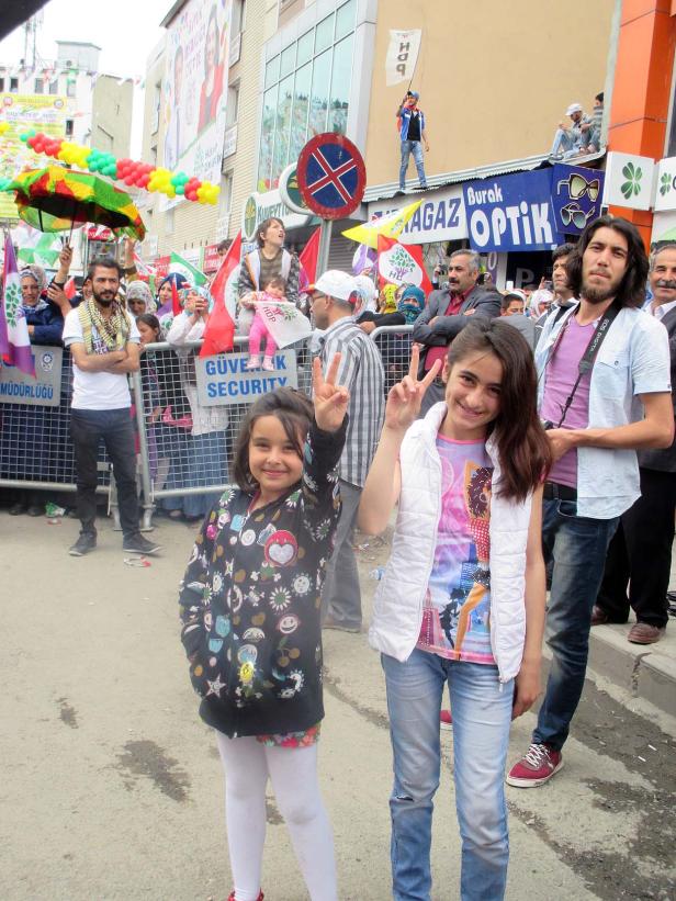Zwei Mädchen zeigen bei einer politischen Kundgebung das Victory-Zeichen.