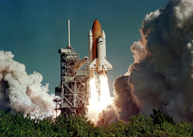 Ein Space Shuttle startet mit einer riesigen Rauchwolke von einer Startrampe.