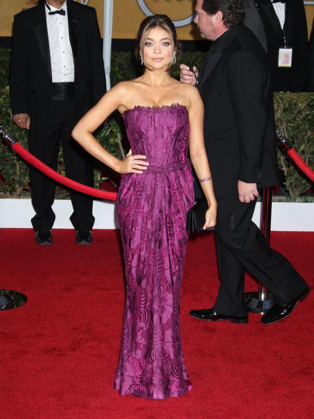 Sarah Hyland in einem trägerlosen, violetten Kleid auf einem roten Teppich.