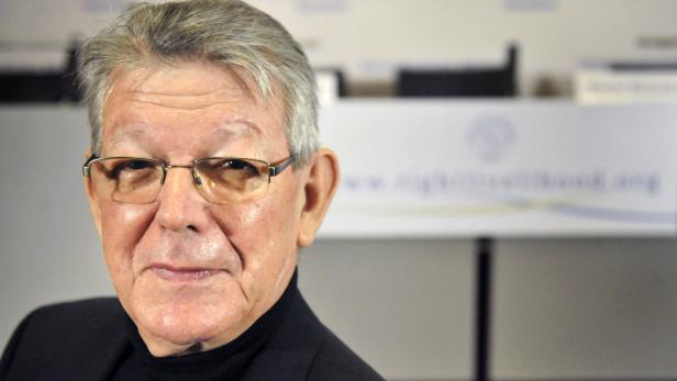 Porträt eines älteren Mannes mit Brille vor einem unscharfen Hintergrund.