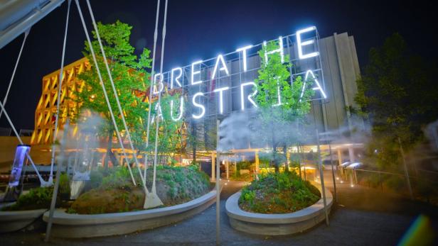 Der österreichische Pavillon mit der leuchtenden Aufschrift „Breathe Austria“ bei Nacht.