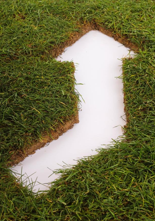 Eine Pfeilform wurde aus Rasenstücken auf einem weißen Hintergrund gelegt.