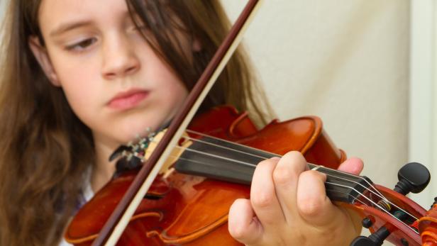 Ein junges Mädchen spielt auf einer Geige.
